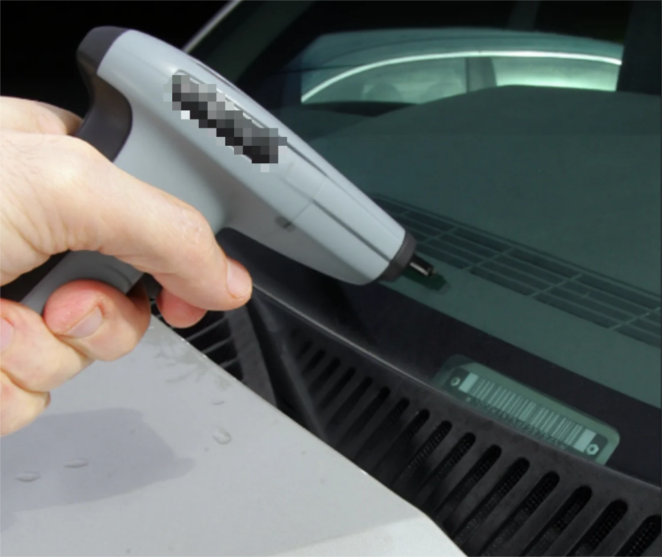 A person scanning a VIN barcode on a car's dashboard.